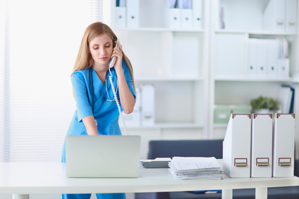 Medical doctor woman with computer and telephone standing at hospital.